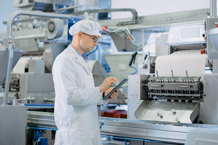 man in a lab coat and hairnet checking a list