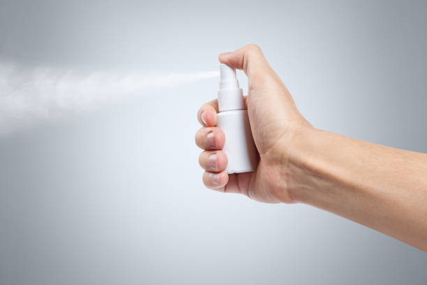 Hand using a spray on gray background