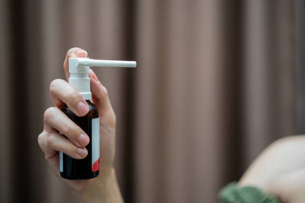 Woman Spray for sore throat, sprinkles it in her mouth.